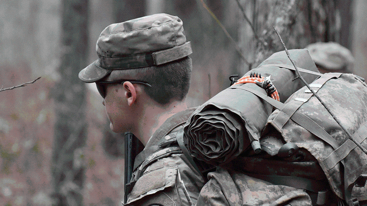 An Auburn Army ROTC cadet stands in the woods during a field exercise