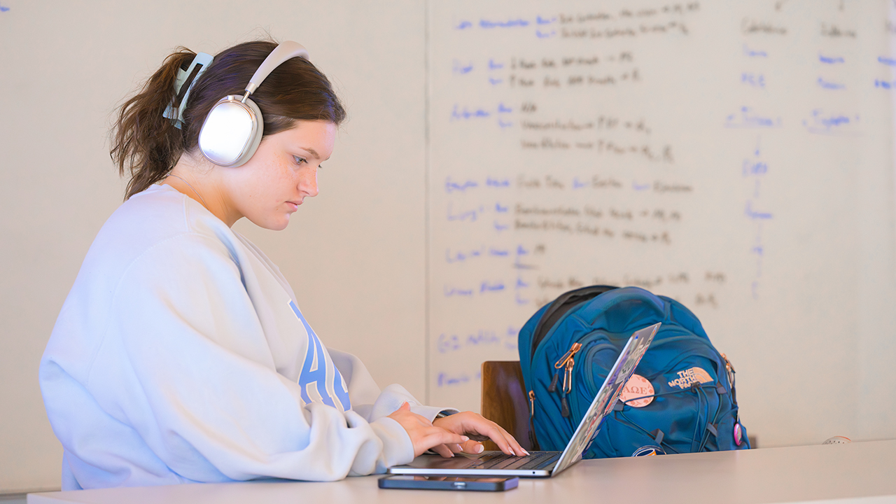 Student with headphones on looking at laptop