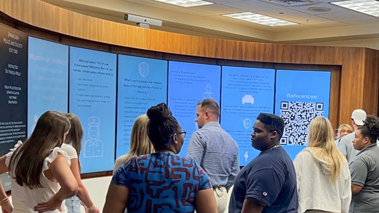 Students gathered around large digital display